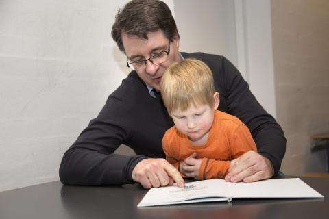 En mand læser højt for et barn