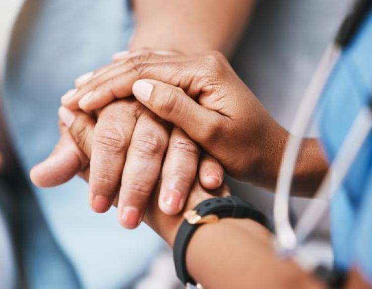 Foto af hænder, en sygeplejerske der holder en patients hånd