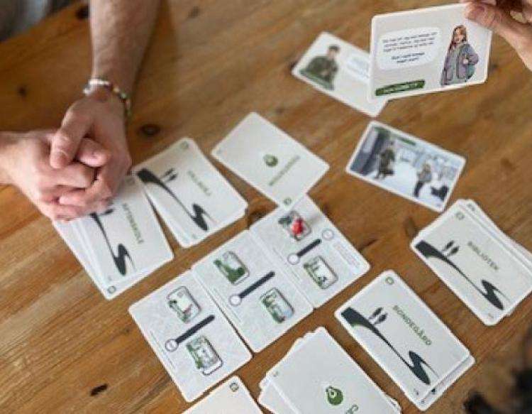 Samtalekortene ligger på et bord, to personer sidder overfor hinanden med kortene imellem sig. 